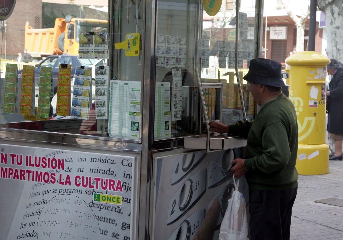 Un hombre compra un cupón en un quiosco de la ONCE.