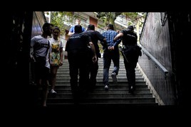Tres policías trasladan a un hombre detenido por robar carteras en una estación del metro.