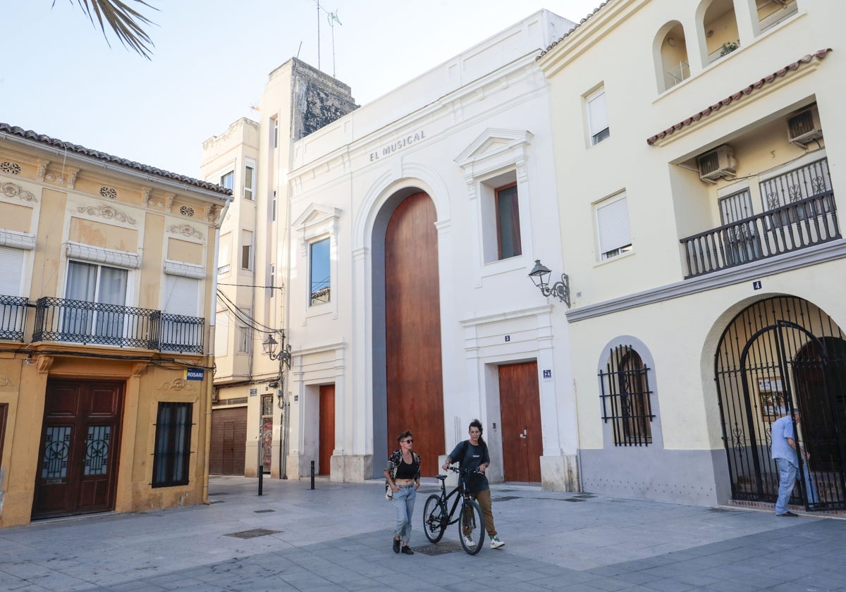 Dos jóvenes pasean por una plaza valenciana.