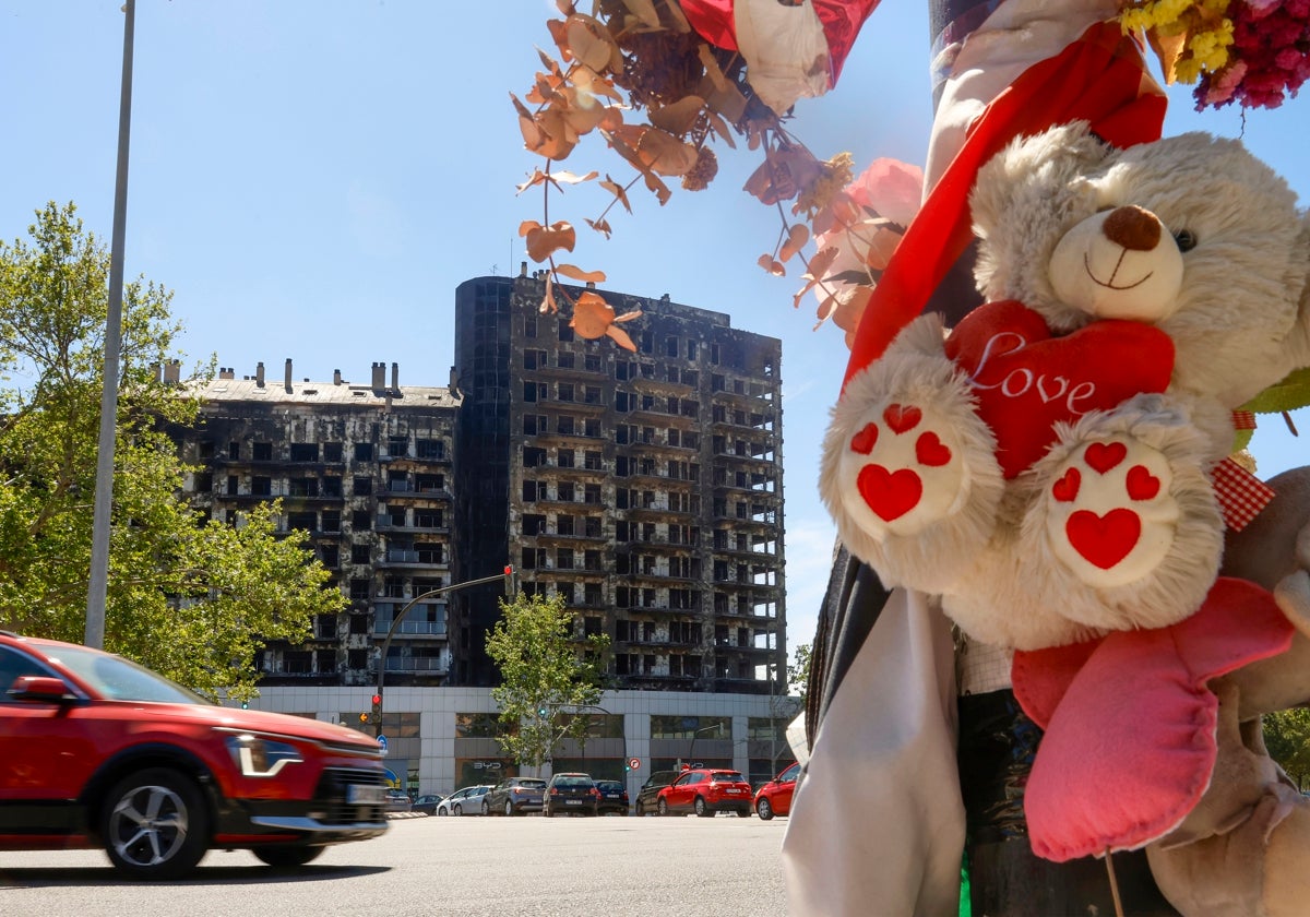 Flores y un peluche, en recuerdo a la tragedia, este domingo ante el edificio calcinado de Campanar