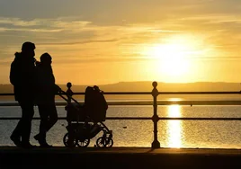 Dos padres pasean un carrito de bebé ante el mar.