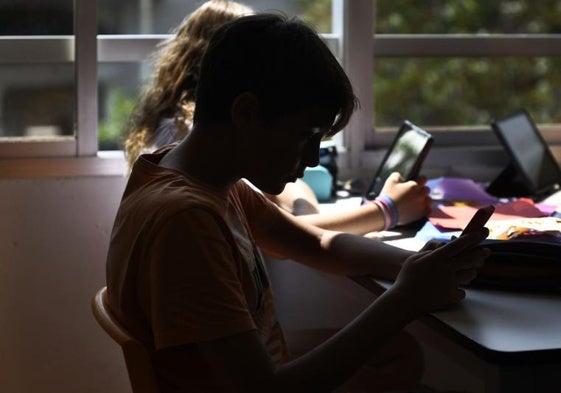 Una niña consulta su móvil en un colegio.