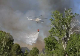 Un helicóptero descarga agua sobre las llamas.