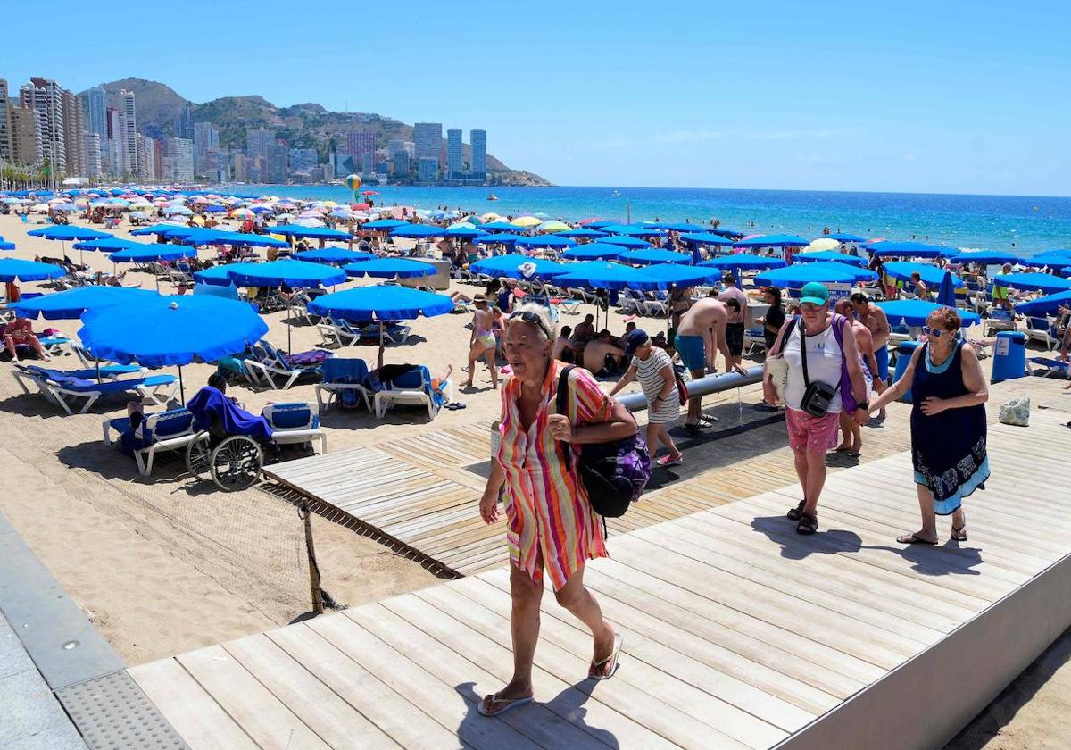 Turistas salen de la playa de Benidorm.