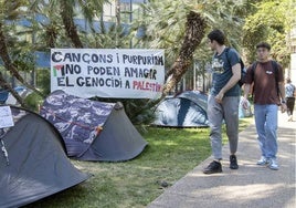 Dos estudiantes leen un cartel de la acampada en defensa de Palestina.