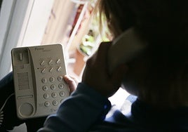 Una mujer realiza una llamada desde su teléfono fijo de casa.