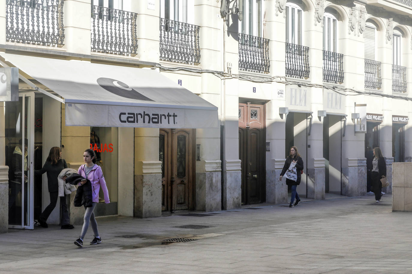 Imagen principal - Arriba, vista de la calle Martínez Ferrando, donde la primera en llegar fue Carhartt. Abajo, los fundadores de Twojeys y Rocío Botella con su equipo, fundadora de The Are.