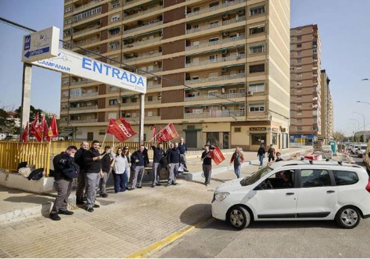 Un usuario se dispone a pasar la inspección de su vehículo ante las protestas de los trabajadores en la estación de Campanar.