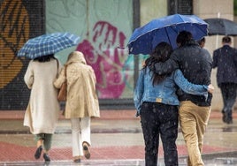 Varias personas se protegen de la lluvia.