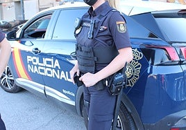 Una policía nacional junto a un coche patrulla.