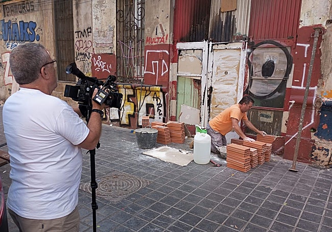 Un cámara de À Punt graba cómo un obrero tapia una de las entradas.