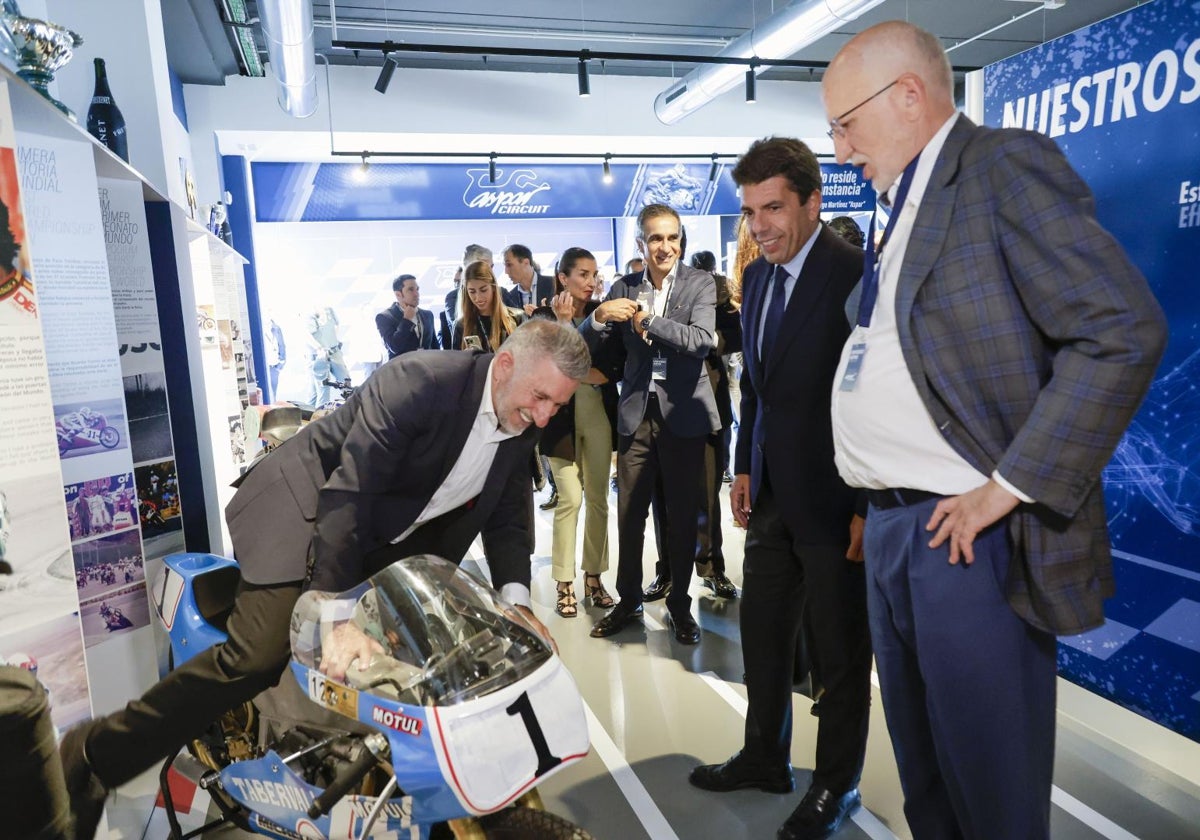 Aspar se sube a una de sus motos que expone en el museo ante el presidente de la Generalitat, Carlos Mazón, y el empresario Juan Roig.