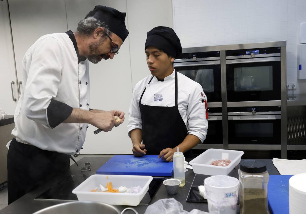 Gabriel Cruz, profesor de cocina del IES El Grau, ayuda a Matías Silva, que se prepara para un concurso gastronómico, en una de las aulas ubicadas en el Veles e Vents.