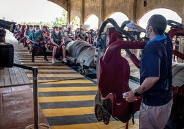 Un trabajador de PortAventura da instrucciones a los visitantes en una montaña rusa. Imagen de archivo.