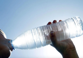 Un joven bebe agua de una botella.