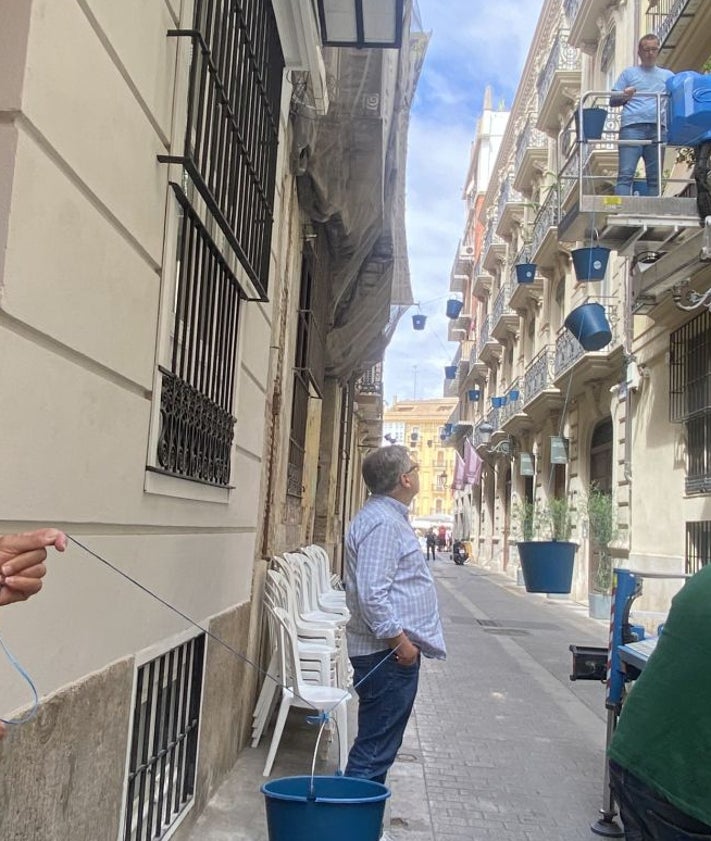 Imagen secundaria 2 - Turistas viendo el montaje en la calle Vabillers; Pepe Camany entregando cubos a un vecino, Quique Sancho, y proceso de instalación de las cuerdas en los balcones.