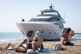 Bañistas, este miércoles, junto al yate encallado en la playa de Pinedo.