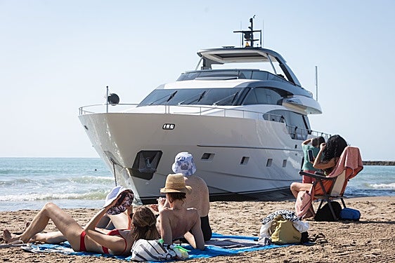 Bañistas, este miércoles, junto al yate encallado en la playa de Pinedo.