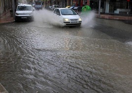 Un coche pasa por una calle anegada a causa de las lluvias en Beniarrés.