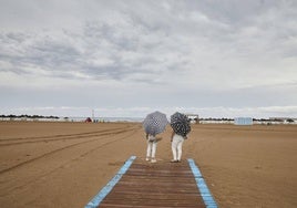 Dos mujeres con paraguas en la playa de Valencia.