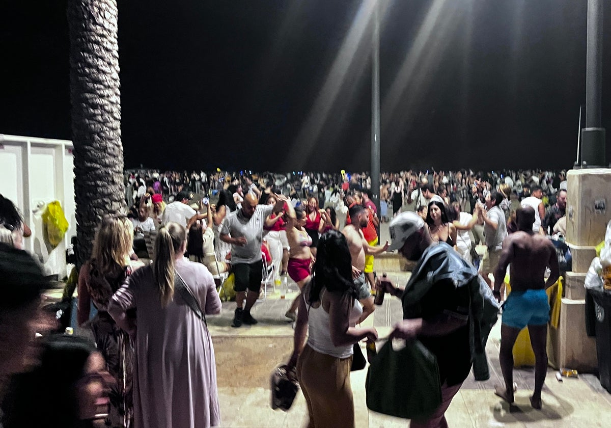 Un grupo de personas baila ante la playa abarrotada este lunes de madrugada.