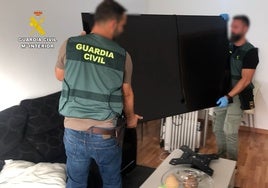 Dos guardias civiles trasladan un televisor intervenido a los ladrones.