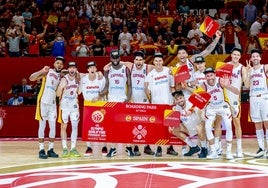 Los jugadores de España posan con el cartel de clasificados para los Juegos de París en el parquet de la Fonteta.