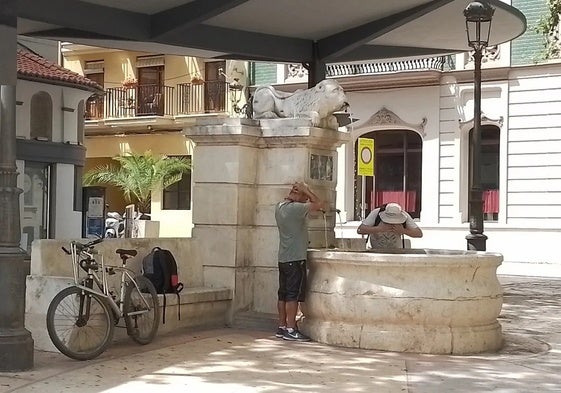 Varios turistas se refrescan en una fuente de Xàtiva.