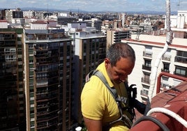 Luis Montero, en plena faena, durante la instalación de un aparato climatizador en una repisa de Valencia.