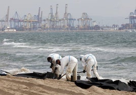 Operarios trabajan en la retirada del vertido de las playas del sur de Valencia.