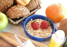 Un desayuno completo con cereales, pan, fruta y huevo duro