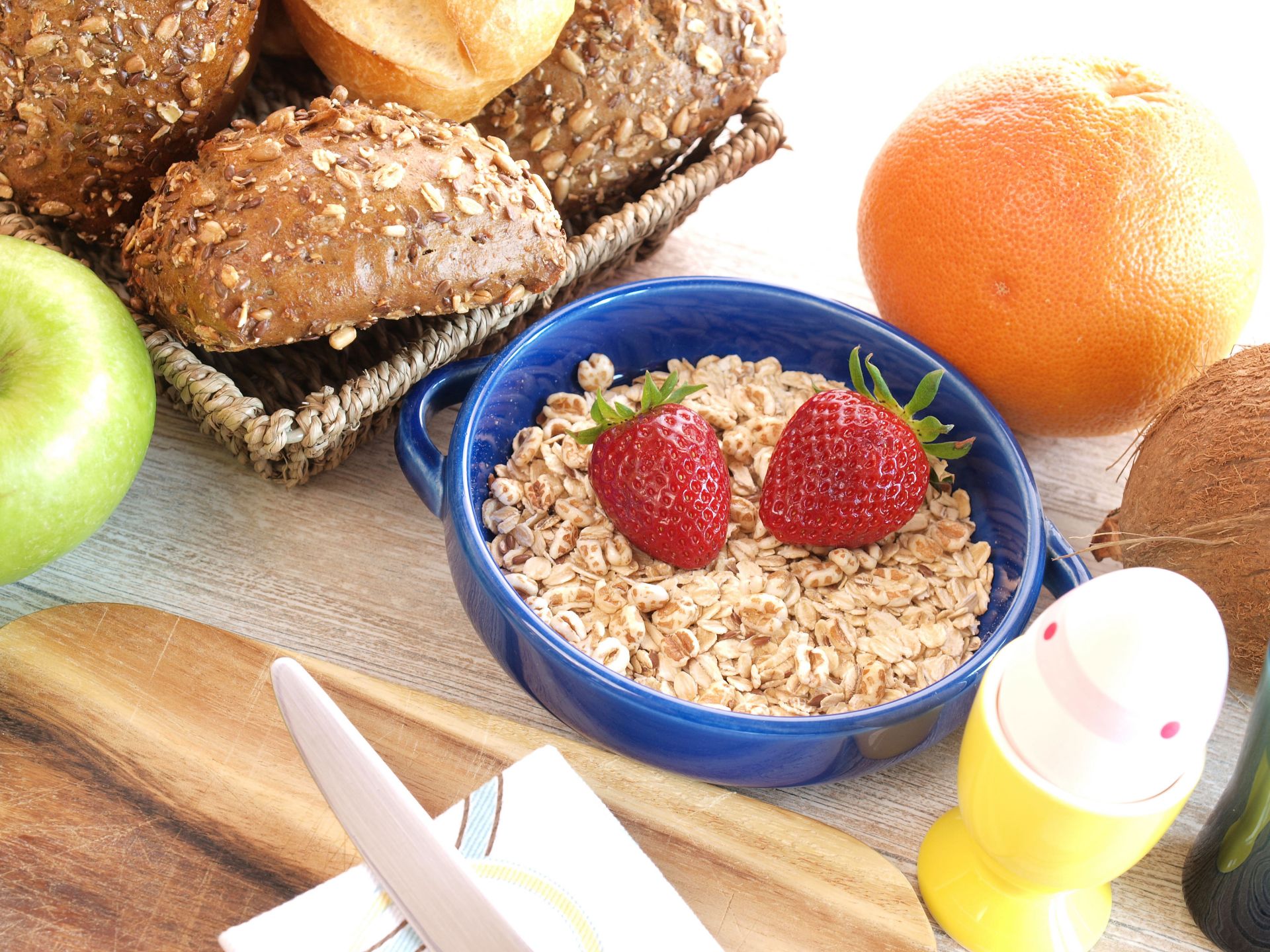 Un desayuno completo con cereales, pan, fruta y huevo duro