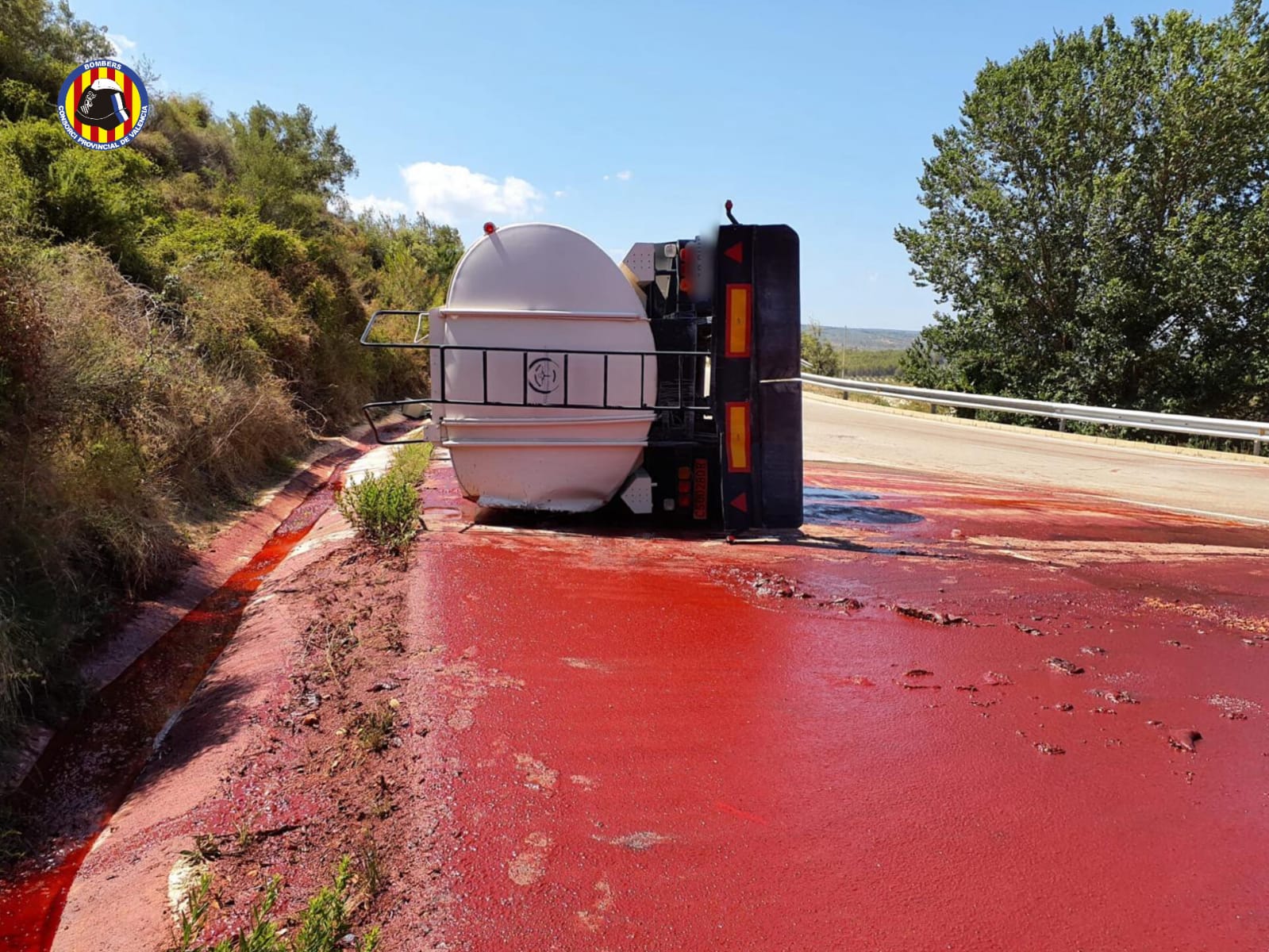 Estado del camión tras volcar, con la carga vertida en la vía.