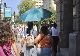 Dos mujeres se protegen con un paraguas del sol abrasador en Valencia.