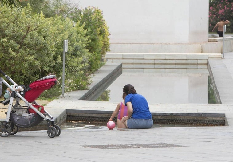 Una familia se refresca, este martes, en el parque Central de Valencia, .