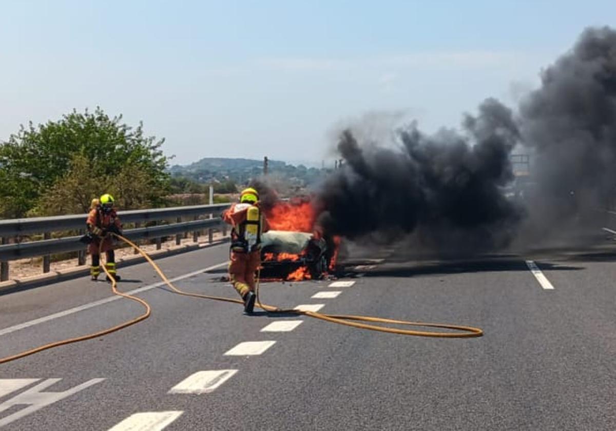 Los bomberos intervienen para controlar las llamas del vehículo incendiado.