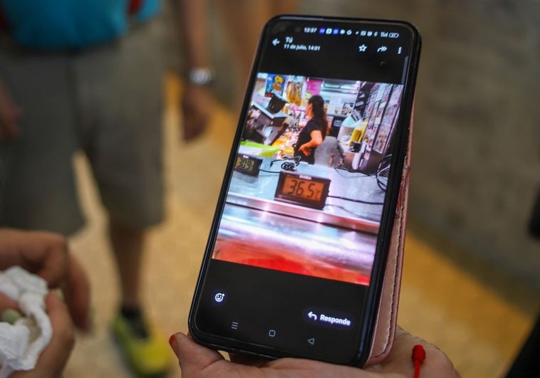 Una vendedora del Mercado Central muestra los 36,5 grados que se ha alcanzado un día este verano en el recinto.