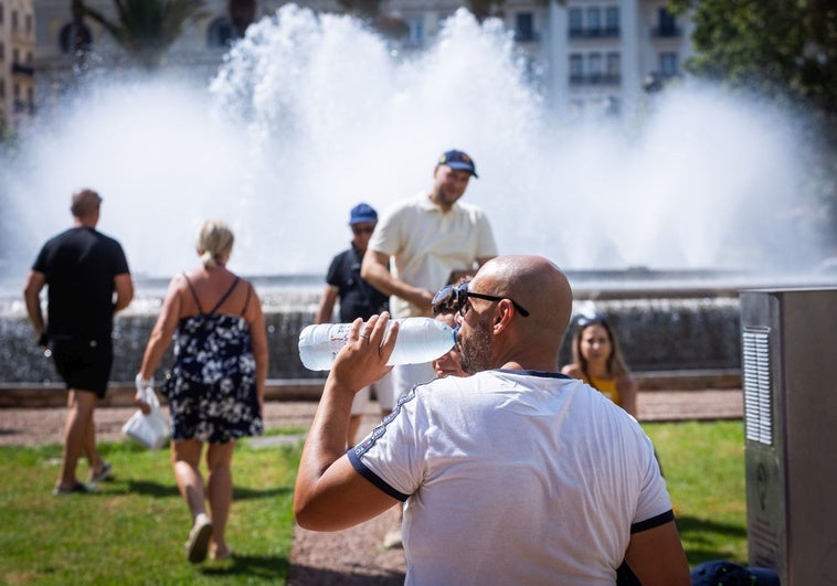 Un hombre bebe agua para refrescarse, este viernes, en el centro de Valencia.