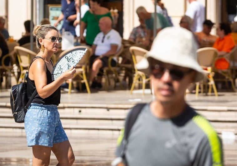 Una mujer se abanica mientras pasea por el centro de Valencia, este jueves.