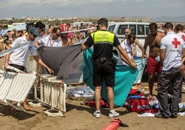 Agentes de la Policía Local de Valencia cubren el cuerpo sin vida de una persona fallecida en una playa de la ciudad.