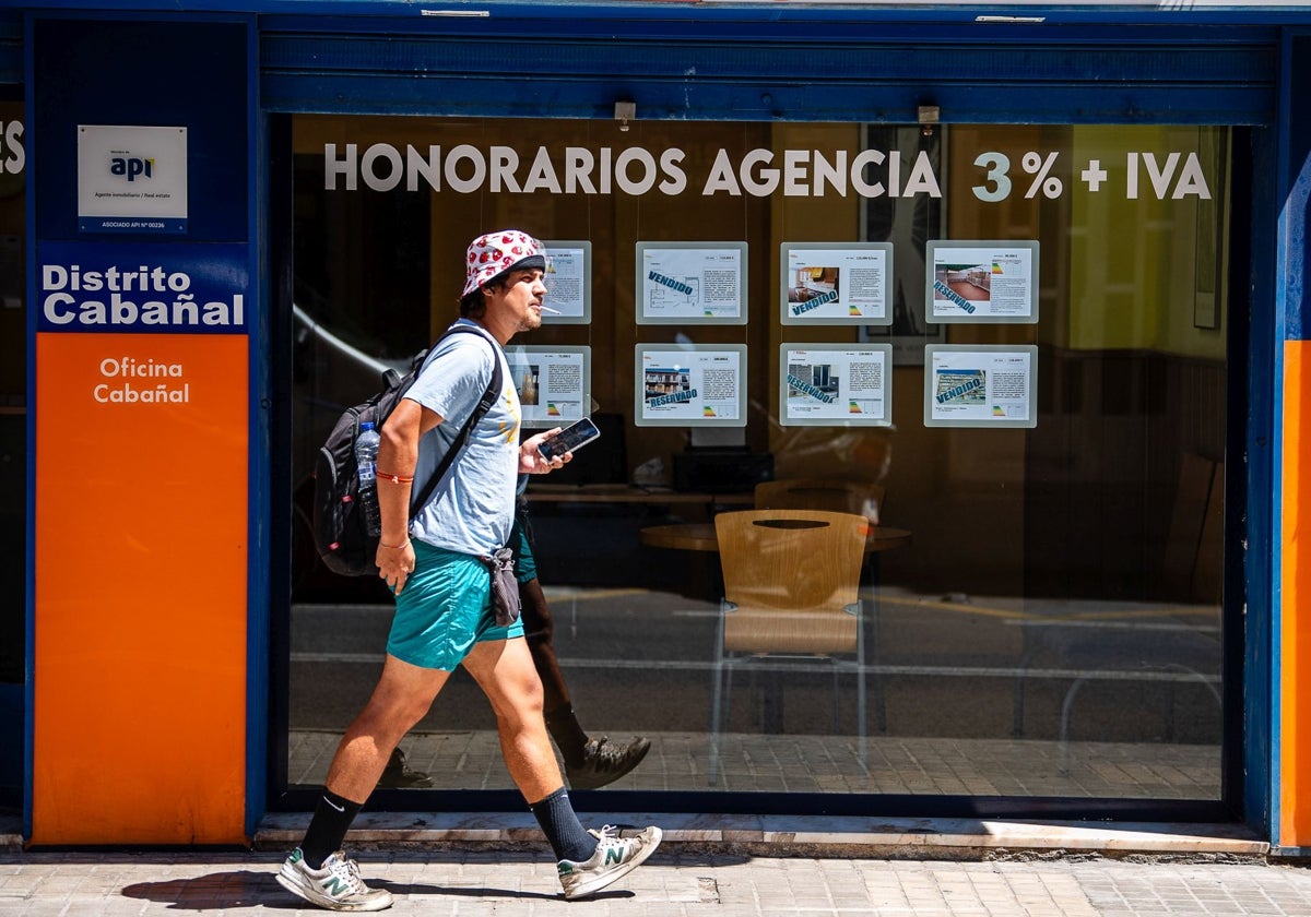 Un joven pasa por delante de una agencia inmobiliaria.