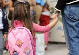 Niña coge de la mano a su madre en su primer día de colegio.