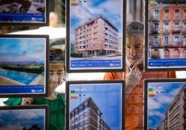 Una pareja observa el escaparate de viviendas de una inmobiliaria.