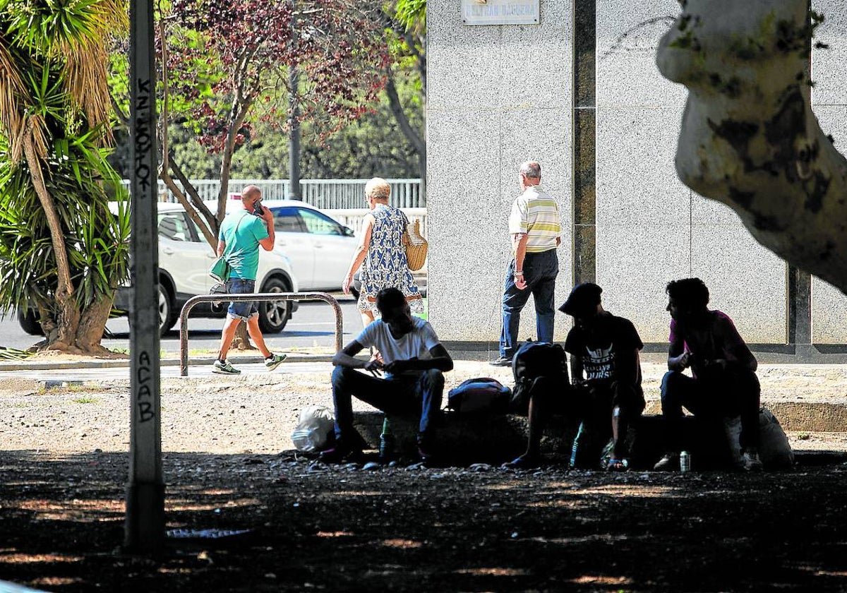 Varias personas sentadas en un parque cerca de la estación de autobuses.