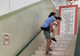 La madre traslada a su hijo por la escalera tras la avería del ascensor.