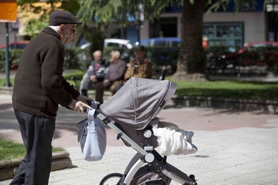 Un hombre mayor pasea por la calle con un carrito de bebé