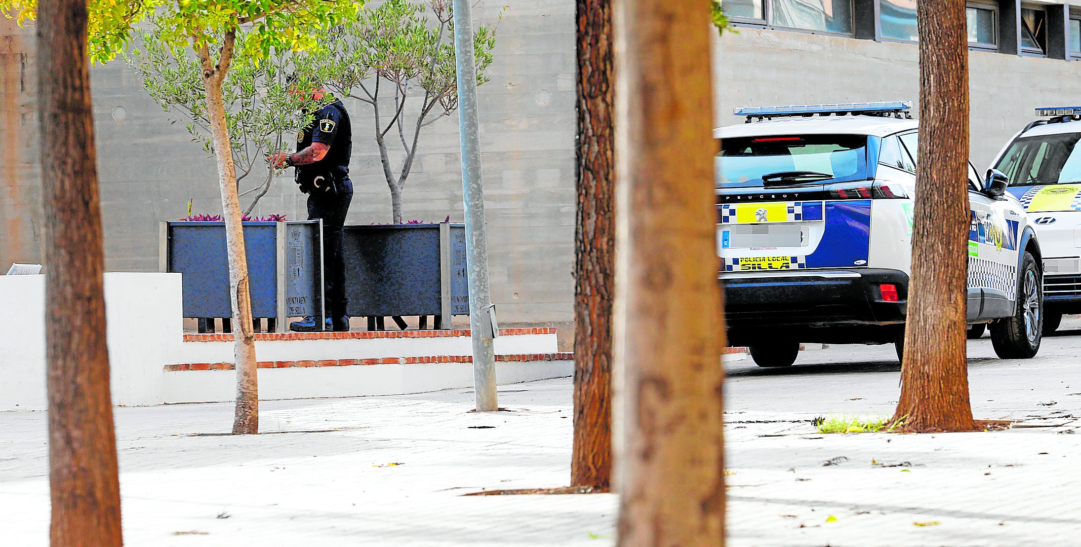 Un agente de la Policía Local de Silla, ayer, junto a un coche patrulla.