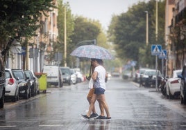 Unos jóvenes se protegen de la lluvia en Valencia.