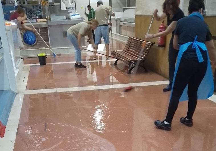 Vendedores achicando el agua que ha inundado el mercado del Cabanyal.