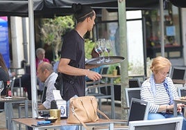Un camarero cobra a una clienta en la terraza de un bar.